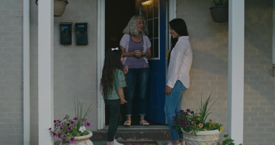 A woman goes knocks on a door and picks her child up from a house and after the two women talk the mother gets a flower and gives it to the woman who had been taking care of her child
