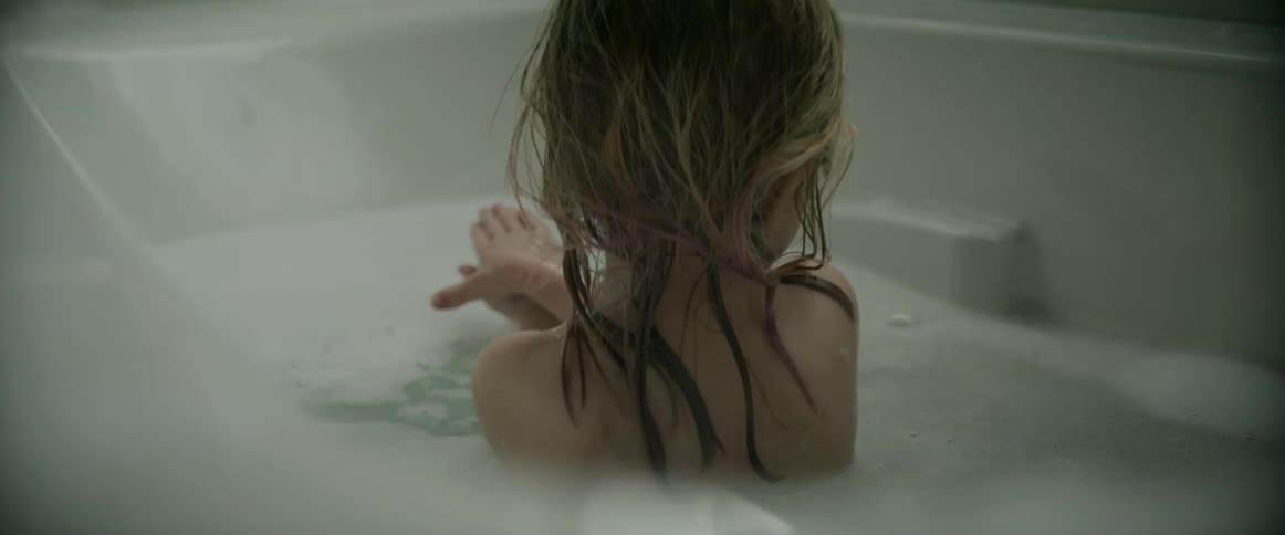 A young girl plays with bubbles during her bath