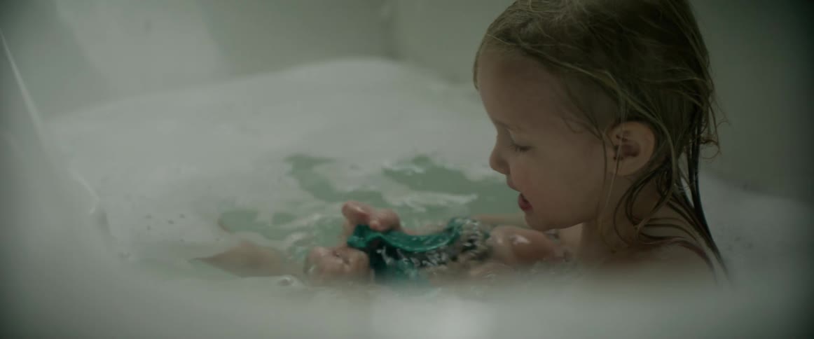 A girl splashes around in the bathtub