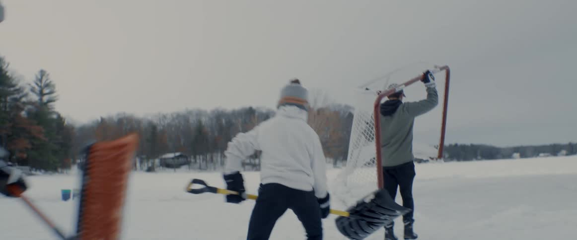 Youths setup portable hockey goal and clear snow from ice for hockey game