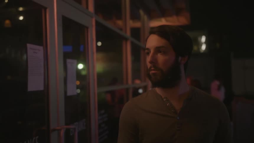 A bearded man walks near a building