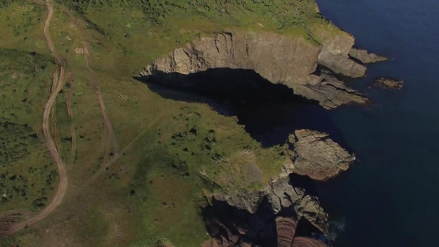 Aerials: Drone flies along cliffs and coastal shore