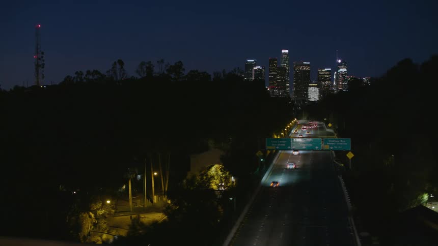 A shot of a busy city freeway during night with high rise buildings visible at a distance