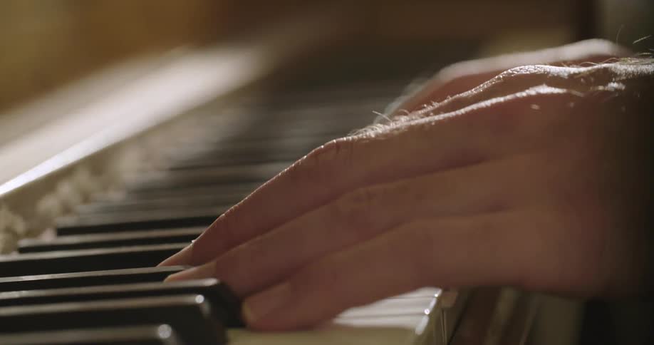 A man's fingers pressing piano keys