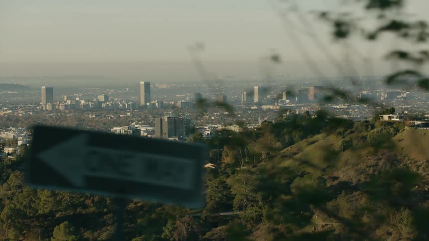 Rolling hills with trees with city buildings in the distance