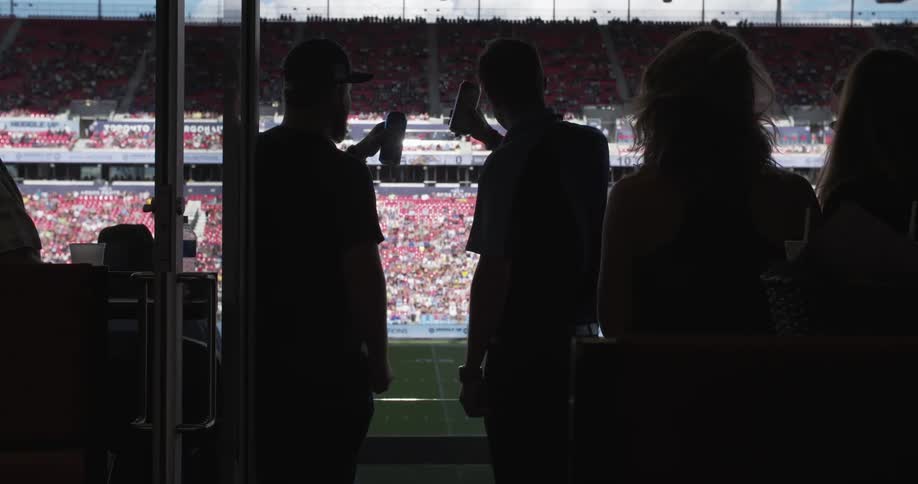 Two men toast while watching a game