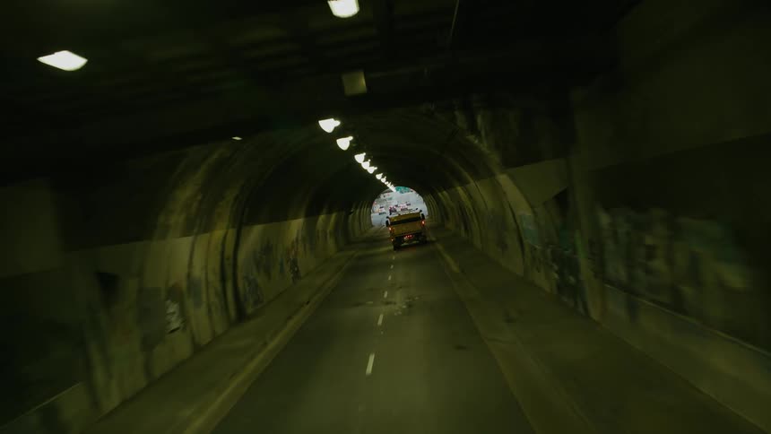 A truck travels through a tunnel and into town