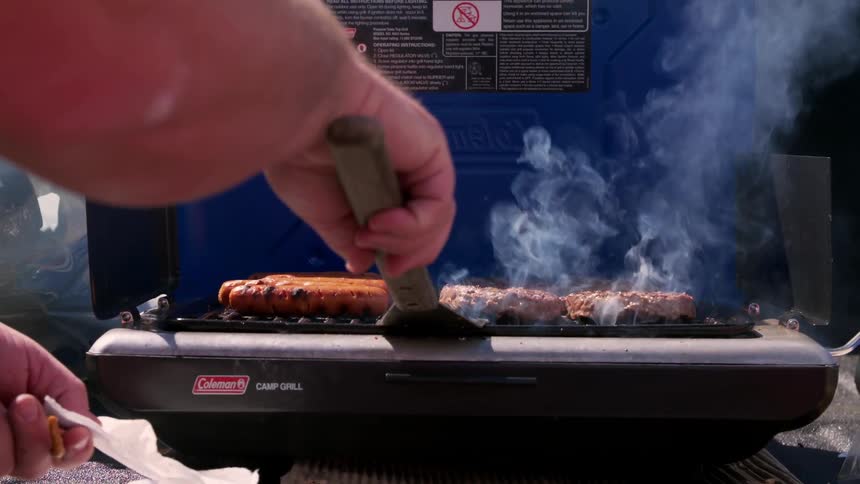 A man is cooking food on a grill outside