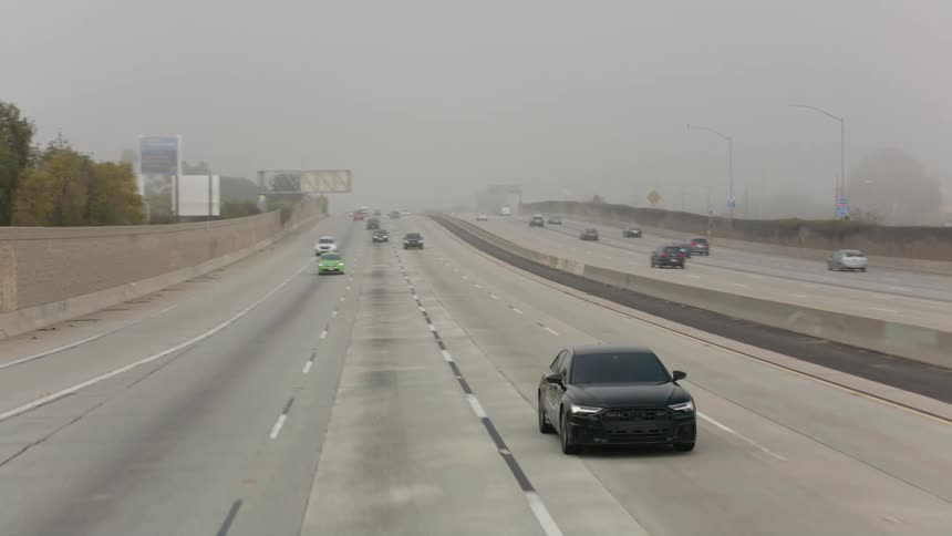 Traffic moves on a highway on a foggy fall day