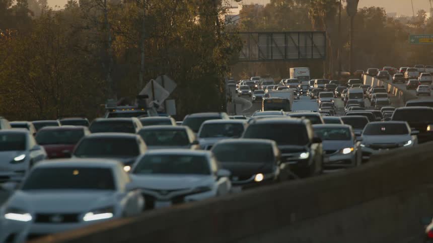 Heavy traffic on a highway moves around a bend during rush hour