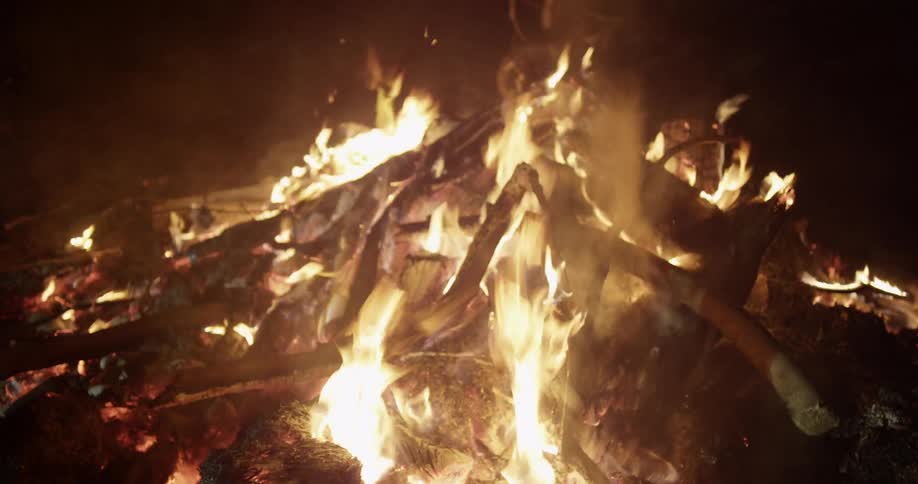 A campfire rages on a field at night