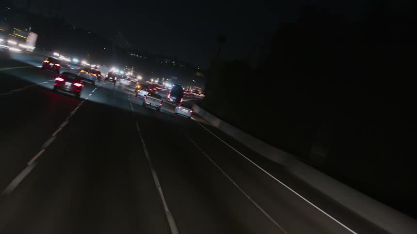 Headlights and tail lights shine brightly on vehicles traveling on a highway at night