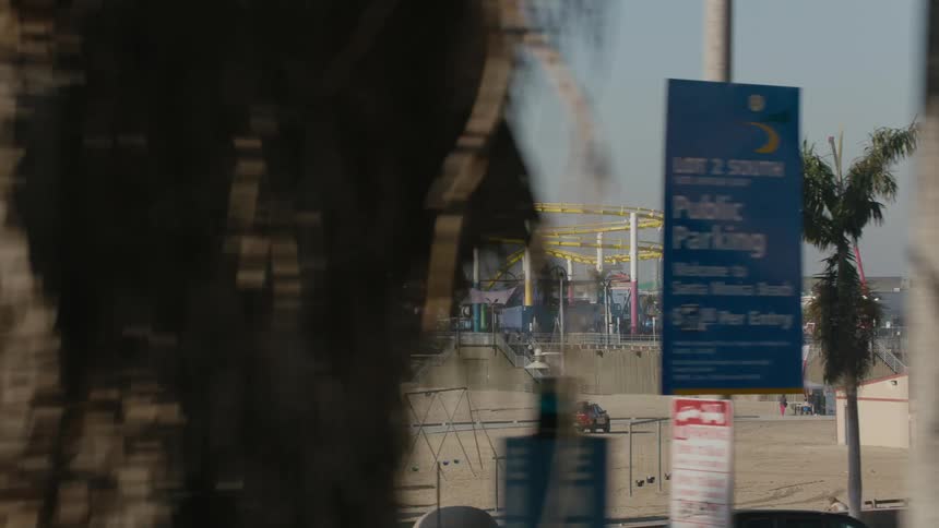 An amusement park in the distance is located next to a sandy beach near the ocean