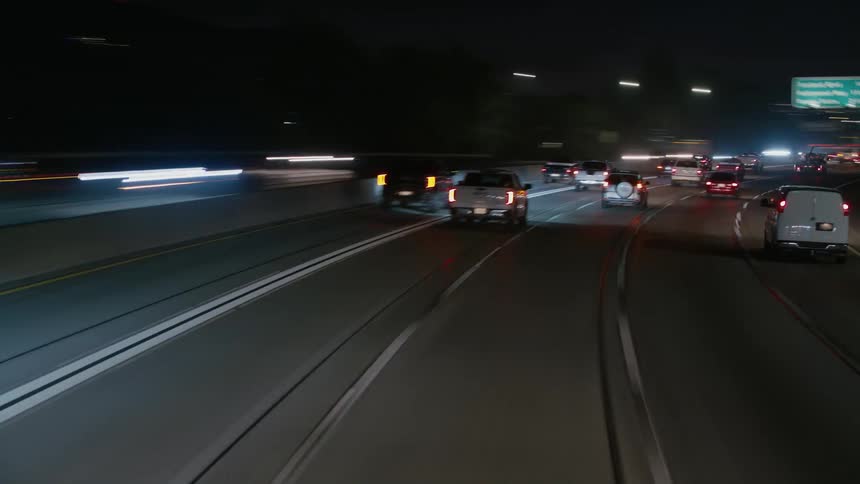 Traffic travels along a freeway through a metropolis at night