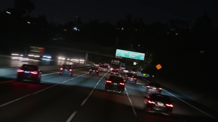 Tail lights and headlights shine as traffic moves on a busy highway at night