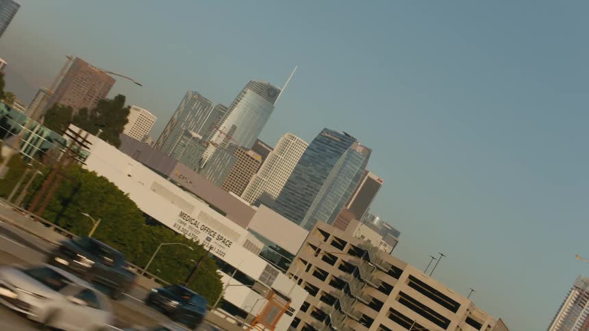 Traffic on a highway traveling out of downtown with tall buildings and skyscrapers rotating in the distance