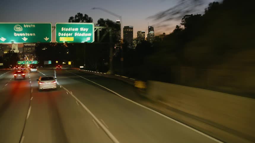 Traffic on a highway traveling downtown with tall buildings and skyscrapers in the distance