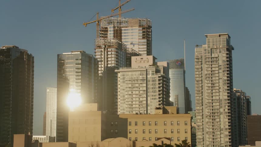 Construction crane sits on a skyscraper under construction in the city on a sunny day