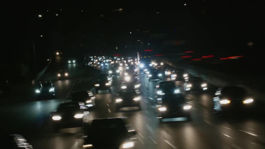Headlights shine brightly on vehicles traveling on a highway at night