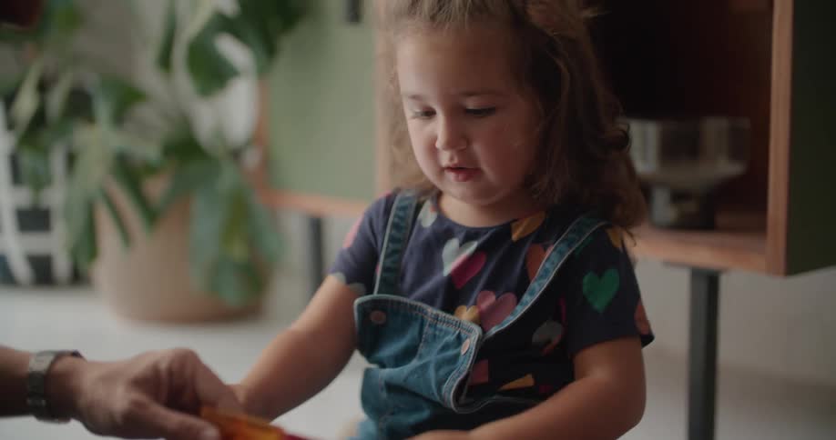 A little girl thinks carefully while building with toys with her dad