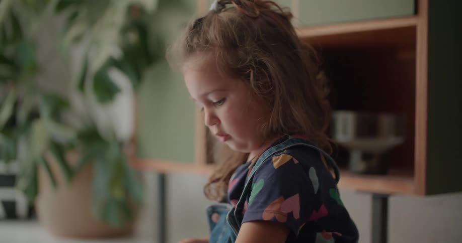 Girl sits on a blanket with an older person that is wearing a wristwatch and they play with colorful plastic squares