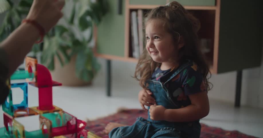 A girl laughs while playing with building squares with her father