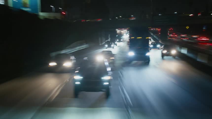 Traffic travels along a large freeway through a metropolis during the night