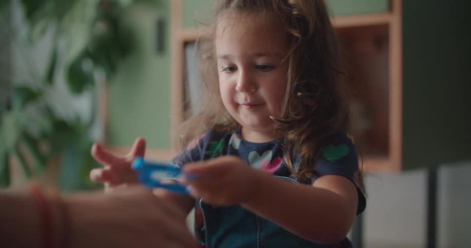 A little girl is playing with toy blocks and a man is helping her build something
