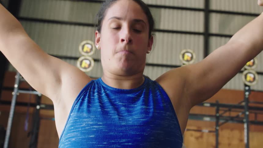 A woman is in a gym working out lifting weights