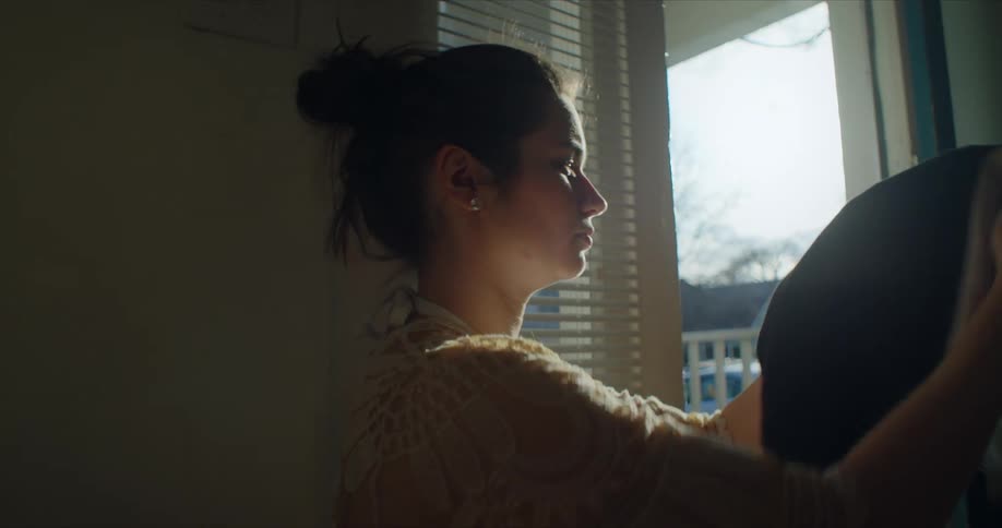 A woman folds clothing indoors during the day