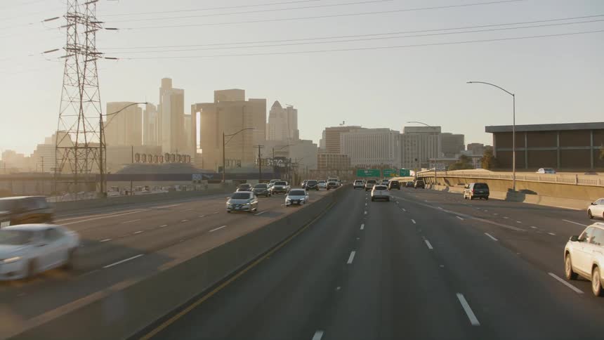 Vehicle drives on city divided highway at sunset