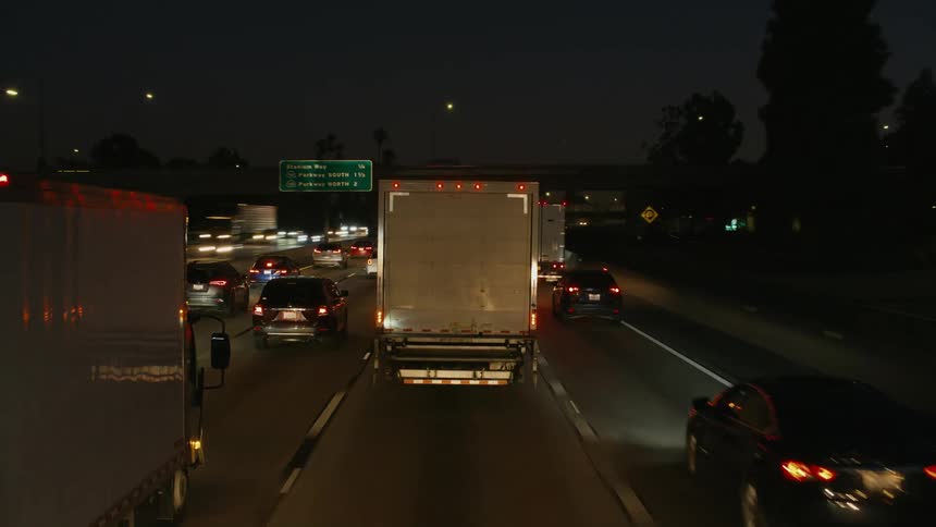 Vehicles are driving fast on a highway at night