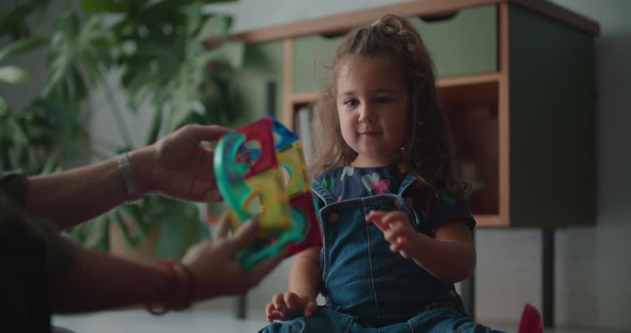 Father plays with his daughter over the rug on the living room at home in the morning