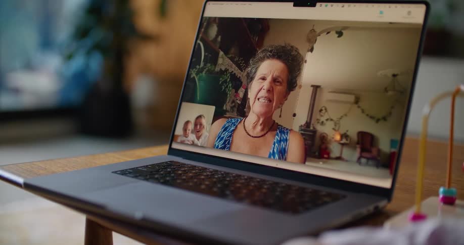 A woman and a baby are having a video conference with an older woman on a laptop computer