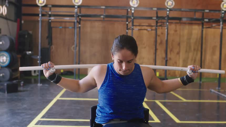 A woman is in a gym working out with a bar