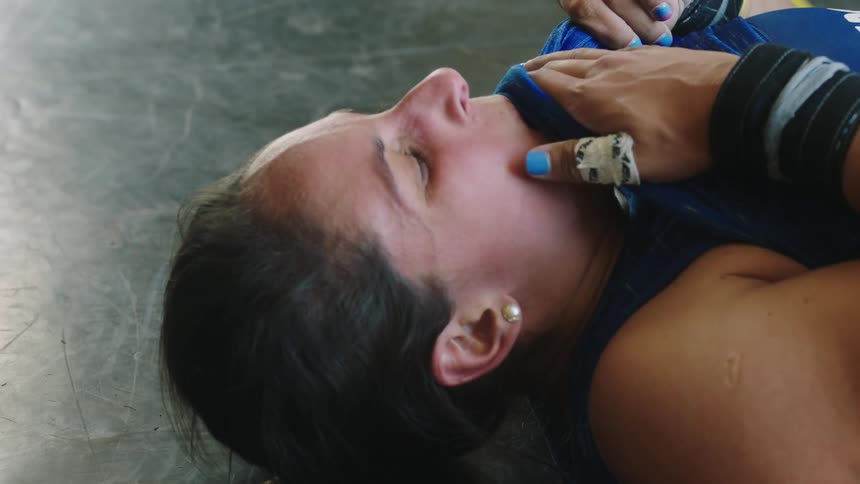 A woman is lying on the floor and she lifts her shirt to wipe her face as she catches her breath