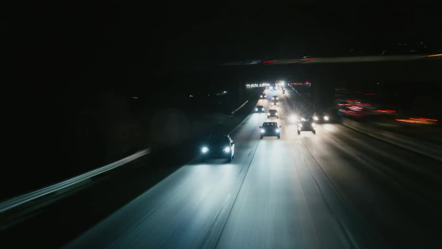 Cars travel with their headlights on at night on the freeway