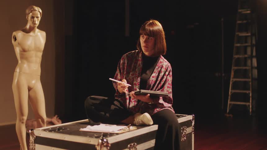 An sketch artist sits on a trunk by a sculpture and sketches