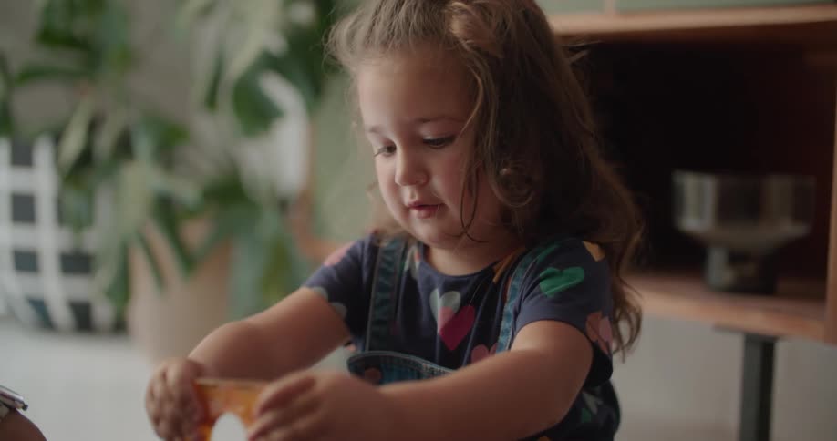A man is sitting on the floor with a little girl playing with toys and high five each other as they make a building
