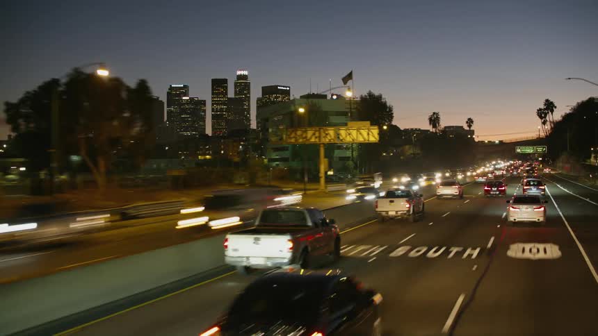 Traffic travels along a highway through a metropolis at sunset