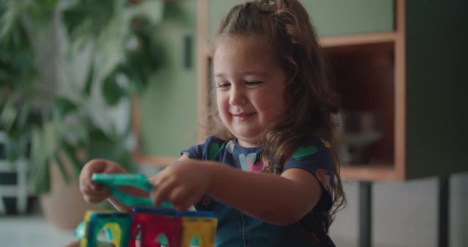 A little girl is playing with toy blocks and a man is helping her with her building