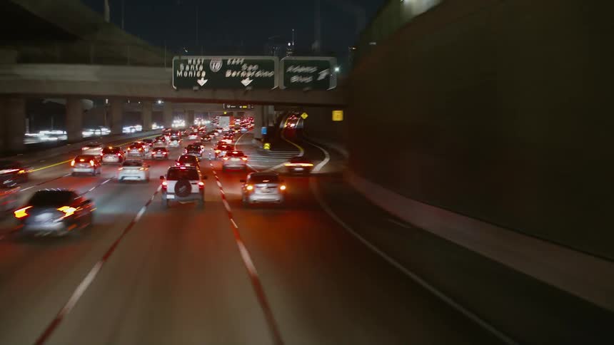Traffic on a highway traveling downtown with tall buildings and skyscrapers in the distance