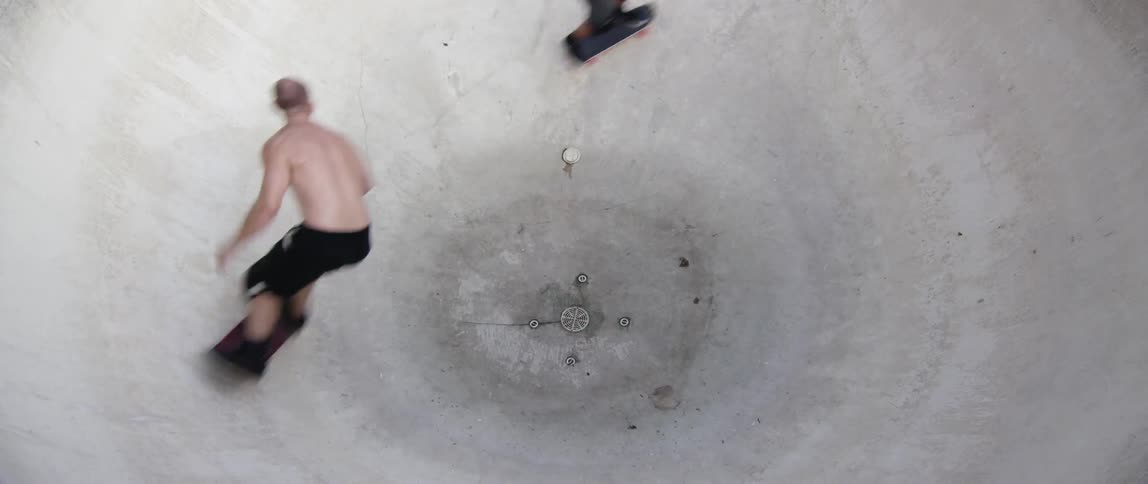 Skateboarders speed through a concrete bowl