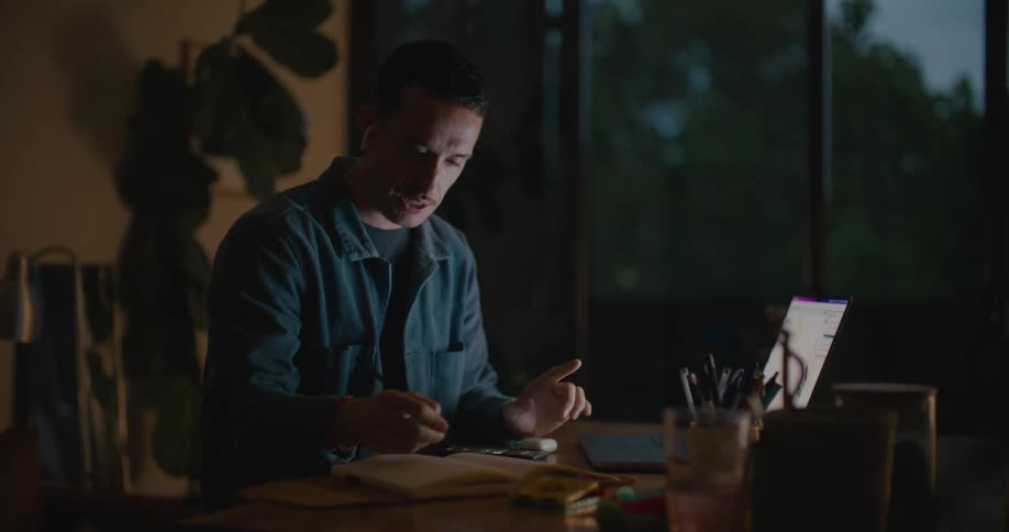 A man is on a laptop and writing things down