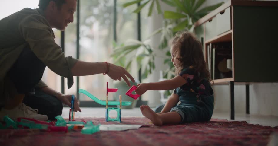 Father plays with his daughter over the rug on the living room at home in the morning
