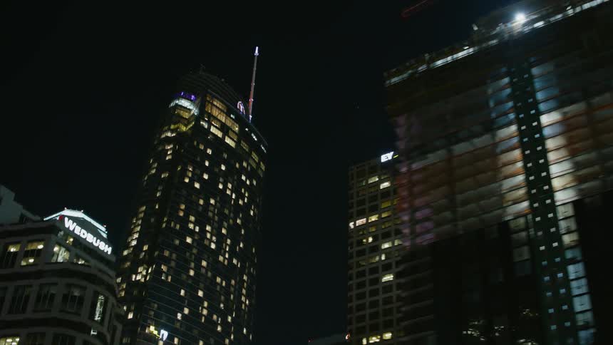 Tall city skyscrapers and towers are lit up in the night sky