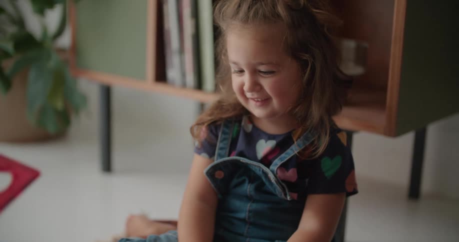A little girl sits at home and shakes her fathers hand as they play