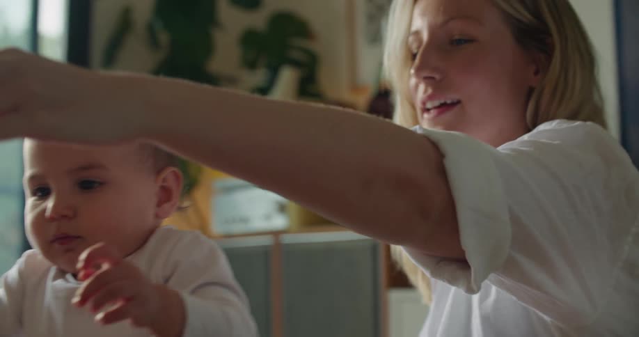 A baby chews on the flower as the mother puts it in the vase