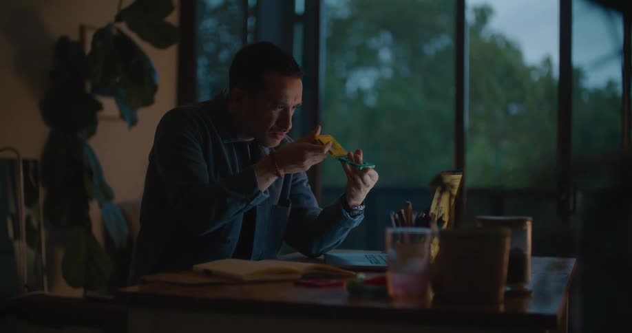 A designer sitting in his home office looking at a prototype of a toy he is creating