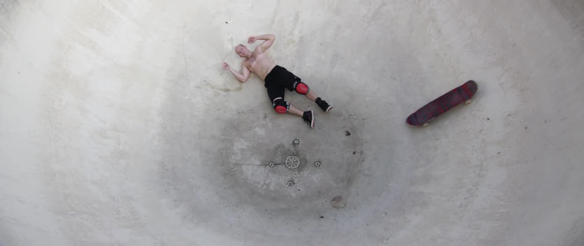 People riding skateboards in a pool one falls off